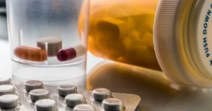 Frasco de medicamentos con pastillas, cápsulas en un vaso y un blíster de tabletas
